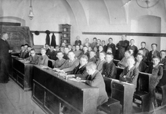 Romania,Transylvania, Cluj-Napoca, Piarista Főgimnázium tanterme., 1910, Cholnoky Tamás, school, classroom, education, tableau, high school, ink bottle, blackboard, boys, teacher, student, school desk, arms crossed over the chest, tile stove, Fortepan #29760