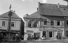 Magyarország, Szentendre, Fő (Marx) tér, Szerb (kalmár) kereszt, ettől jobbra a Török köz és mögötte a Szent Péter-Pál-templom tornya látható., 1955, Storymap.hu, cégtábla, emlékmű, lovaskocsi, utcakép, életkép, étterem, szamár, fogat, sikátor, épület, kereszt_jelkép, kordé, Fortepan #30862