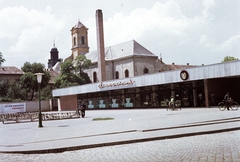 Magyarország, Kecskemét, Horváth Cirill tér, Piaccsarnok, háttérben a Szentháromság piarista templom és a Piarista Gimnázium tornya., 1966, Építésügyi Dokumentációs és Információs Központ, VÁTI, kerékpár, templom, lámpaoszlop, áruház, kockakő, piarista rend, színes, Fortepan #30991