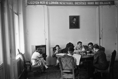 Magyarország, Budapest XIV., Stefánia (Vorosilov) út, Petőfi-kollégium, történészhallgatók a társalgóban., 1949, Kovács Márton Ernő, cigaretta, dohányzás, olvasás, sakk, életkép, bútor, rádió, újság, enteriőr, asztal, szék, jelmondat, karosszék, Petőfi-ábrázolás, Budapest, Fortepan #33099