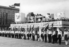 Magyarország, Budapest XIV., Ötvenhatosok tere (Felvonulási tér), a tribün mögött a Benczúr utca sarkán álló épület látszik. A felvétel a KISZ fogalomtételi ünnepségén 1968. április 4-én készült., 1968, Angyalföldi Helytörténeti Gyűjtemény, úttörő, zászló, ünnepség, jelmondat, április 4, KISZ, Budapest, Fortepan #39671