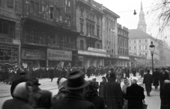 Magyarország, Budapest V., Kossuth Lajos utca a Semmelweis utca felől a Ferenciek tere (Felszabadulás tér) felé nézve., 1956, Nagy Gyula, háborús kár, cégtábla, tömeg, forradalom, járókelő, utcakép, lámpaoszlop, áruház, üzletportál, csoportosulás, Budapest, Fortepan #39965