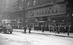 Magyarország, Budapest V., Ferenciek tere (Egyetem utca), szemben a Curia utca torkolata., 1956, Nagy Gyula, háborús kár, üzlet, cégtábla, forradalom, járókelő, utcakép, neonreklám, lámpaoszlop, üzletportál, csoportosulás, automobil, Skoda 1101 VO/P Colonial, sorbanállás, terepjáró, Budapest, üvegtégla, Fortepan #39967