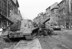 Hungary, Budapest VIII., a József körút a Corvin (Kisfaludy) köznél. Harcképtelenné tett ISZU-152-es szovjet rohamlövegek, a háttérben egy T-34/85 harckocsi., 1956, Nagy Gyula, war damage, Soviet brand, revolution, tank, wreck, untitled, combat vehicle, ISU-152 assault gun, Budapest, damaged building, Fortepan #40262