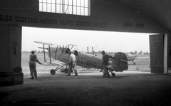 Magyarország, Szentes, repülőtér. A hangárból kitolnak egy Bücker Bü 131 "Jungmann" repülőgépet, magyar neve "Csíz"., 1949, UVATERV, közlekedés, repülőgép, hangár, repülőtér, Bücker-márka, jelmondat, Bücker Bü 131, Fortepan #4253