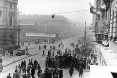 Magyarország, Budapest VIII.,Budapest VII., Rákóczi út az EMKE háztól a Rókus kórház felé nézve. Balra a Blaha Lujza téren a Nemzeti Színház., 1956, Pesti Srác2, zászló, felirat, forradalom, nemzeti színház, járókelő, utcakép, járműroncs, Fellner és Helmer-terv, automobil, metróépítés, eklektikus építészet, Budapest, Fortepan #46765