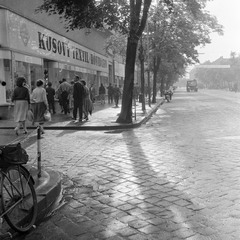 Slovakia, Lučenec, ulica Tomása Garrigue Masaryka, balra az ulica Jána Amosa Komenského torkolata., 1959, Zsanda Zsolt, Vajszada Károly, Czechoslovakia, clothing store, bilingual sign, bicycle, cobblestones, Fortepan #53756