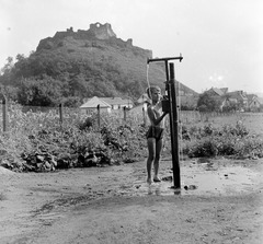 Slovakia, Fiľakovo, Farská lúka (Paprét), az egyik "csevice" forrás, háttérben a vár., 1959, Zsanda Zsolt, Vajszada Károly, Czechoslovakia, well, castle ruins, barefoot, Fortepan #53792