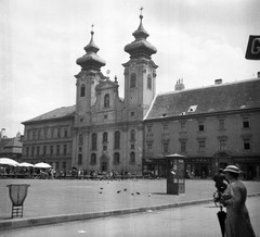 Magyarország, Győr, Széchenyi tér, Loyolai Szent Ignác bencés templom. Mellette balra a Czuczor Gergely Bencés Gimnázium, 1939, Magyar Bálint, templom, piac, utcakép, életkép, telefonfülke, pék, szemetes, Fortepan #55946