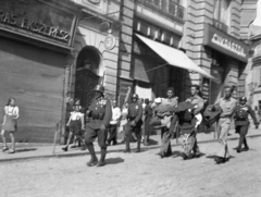 Magyarország, Veszprém, A Szabadság tér - Kossuth utca sarkán, a Takarék-udvar előtt fogságba esett amerikai repülősöket kísérnek., 1944, Karabélyos Péter, egyenruha, cégtábla, életkép, cukrászda, üzletportál, hadifogoly, katona, bámészkodás, órás, cégér, ejtőernyő, amerikai katona, napellenző, zárvatartás, Fortepan #57167