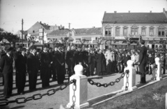 Magyarország, Nyíregyháza, Hősök tere (Bessenyei tér), ünnepség a Hősök szobra előtt. Háttérben az NyVKV (Nyíregyházavidéki Kisvasutak) szerelvénye és Osgyáni József gyógyszertára (korábban: Korányi-patika)., 1938, Zsanda Zsolt, cégtábla, óra, utcakép, ünnepség, diáksapka, szónok, kisvasút, Fortepan #58733