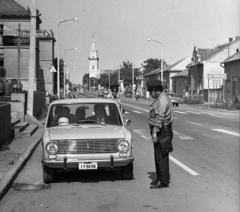 Hungary, Törökszentmiklós, Kossuth Lajos utca, háttérben a református templom., 1976, Magyar Rendőr, cop, number plate, bicycle, crosswalk, Fortepan #66217