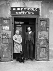 Hungary, Bicske, Kossuth Lajos tér (Vásártér). Az Otthon vendéglő tulajdonosa feleségével., 1946, Lissák Tivadar, ad, dog, restaurant, sign-board, store display, standing in door, Fortepan #73006