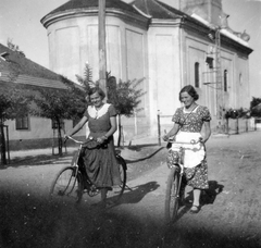 Hungary, Laslovo, Kossuth Lajos utca, háttérben a Szent Márton templom., 1950, Fortepan, portrait, smile, bicycle, summer dresses, lady, dirt road, apron, Fortepan #7370