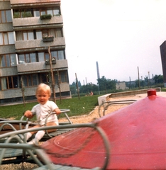 Magyarország, Budapest XIV., játszótér a Róna park 4. számú ház előtt, a kép jobb szélén az Ungvár utca 52/c, középen a háttérben az egyemeletes épület a Kriván utca 6. számú ház., 1973, PRL, játszótér, színes, körhinta, homokozó, Budapest, panelház, Fortepan #76215