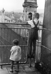 Magyarország, Budapest V., Galamb utca 5., kilátás Buda felé az ortodox székesegyház felett. A távolban a Szent Katalin-templom látszik a Tabánban., 1951, Vojnich Pál, terasz, Budapest, kisfiú, kíváncsiság, rács, Fortepan #76396