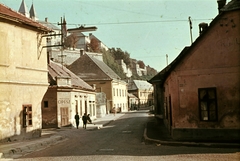 Magyarország, Veszprém, Szent István (Vörös Október) utca - Eszterházy Antal (Szabad nép) utca sarok, szemben a Jókai Mór utca. Balra fenn a Vár., 1966, Herth Viktória dr, Bodó Emma, színes, utcakép, villanyoszlop, cipész, villanyoszlop, közvilágítás, Fortepan #76504