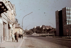 Magyarország, Veszprém, Kossuth Lajos utca a Budapest út felé nézve. A bal oldali házsor helyén ma a "Lordok Háza" áll., 1966, Herth Viktória dr, Bodó Emma, színes, motorkerékpár, utcakép, erkély, lámpaoszlop, katona, kuka, szemetes, közvilágítás, tábla, ruhaüzlet, Fortepan #76507