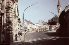 Magyarország, Veszprém, Kossuth Lajos utca a Brusznyai Árpád utca (Bajcsy-Zsilinszky út) felől nézve. Jobbra az evangélikus templom tornya., 1966, Herth Viktória dr, Bodó Emma, templom, színes, plakát, utcakép, automobil, villanyoszlop, ruhaüzlet, hirdetmény, gyalogátkelő, Fortepan #76522