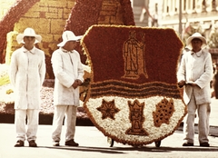 Magyarország, Debrecen, Piac utca (Vörös Hadsereg útja) a Gambrinus köz torkolatánál. Virágkarnevál, a Lenin Kohászati Művek kocsija., 1975, Ötvös Gergely, színes, virág, címer, virágkarnevál, kohászat, pódiumautó, Fortepan #77913