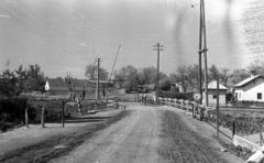 Magyarország, Vértesacsa, Fő utca a katolikus templomtól a vasúti átjáró felé nézve., 1951, UVATERV, falu, híd, utcakép, sorompó, földút, villanypózna, Fortepan #80177