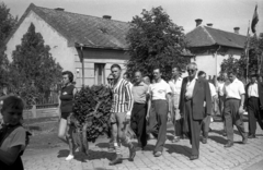 Magyarország, Kisújszállás, Rákóczi utca az Illésy utca felől a Csatorna utca felé nézve., 1960, Morvay Kinga, Morvay Lajos, felvonulás, koszorú, kockakő, sportdressz, Fortepan #84451