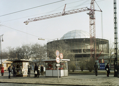 Magyarország, Budapest X., Szent László (Pataky István) tér, a "Pataky" Művelődési ház építése., 1975, Kádas Tibor, színes, építkezés, útjelző tábla, daru, újságárus, virágárus, modern építészet, Budapest, Tóth Dezső-terv, Fortepan #84841