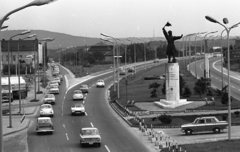 Magyarország, Budapest XI., Osztapenko szobor a Balatoni út és az M1-M7 közös szakaszánál a Budaörsi út irányából nézve., 1976, Urbán Tamás, szobor, útjelző tábla, Lada-márka, Volkswagen-márka, Ford-márka, Citroen-márka, rendőrjármű, Agip-márka, Osztapenkó-ábrázolás, Budapest, Fortepan #89303