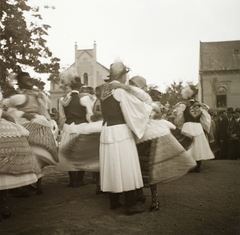 Magyarország, Sióagárd, Hősök tere, szemben a Kossuth utca 23. és 25. számú ház. A felvétel az OMGE tanulmányi társaságának a községben tett látogatása alkalmával készült., 1936, Ebner, templom, tánc, népviselet, néptánc, Fortepan #92229