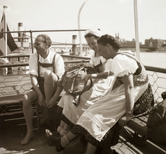 Magyarország, Budapest V., a Belgrád (Ferenc József) rakpartnál kikötött hajó fedélzete, háttérben a Szabadság (Ferenc József) híd., 1940, Ebner, népviselet, hátizsák, hajókirándulás, Budapest, Fortepan #92315