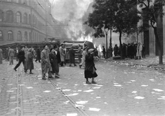 Magyarország, Budapest VIII., Blaha Lujza tér, felborított és lángoló villamosok a József körútnál. Háttérben a Népszínház utca torkolatánál álló épületek láthatók., 1956, Hofbauer Róbert, forradalom, villamos, járműroncs, tűz, gázlámpa, Budapest, Fortepan #93002