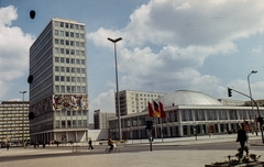 Németország, Berlin, Kelet-Berlin, Alexanderplatz, balra a Haus des Lehrers, jobbra a Kongresszusi Központ., 1970, LHM, színes, zászló, NDK, szocreál, Kelet-Berlin, modern építészet, falfestmény, Hermann Henselmann-terv, Walter Womacka-terv, Fortepan #93576