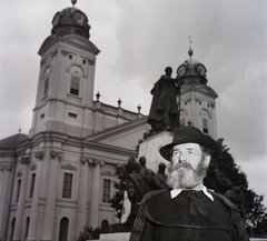 Magyarország, Debrecen, Kossuth tér, a Kossuth-szoborcsoport és a Református Nagytemplom. Előtérben Füley Gusztáv egykori nyíregyházi pénzügyi tanácsos, akkori debreceni szóhasználat szerint "Kossuth Lajos bácsi"., 1955, Kotnyek Antal, Hires Tibor, kalap, templom, szobor, férfi, klasszicizmus, talár, timpanon, Kossuth Lajos-ábrázolás, szoborcsoport, Rabl Károly-terv, Péchy Mihály-terv, híres ember, képarány: négyzetes, toronyóra, Fortepan #96524